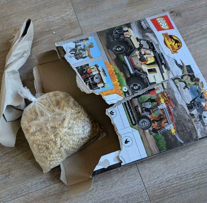 Caja de LEGO Jurassic World dañada con pasta dentro, ejemplo divertido de compras online que salieron mal.