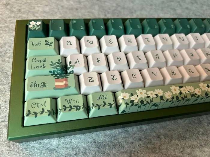 Mechanical keyboard with cottage core aesthetics keycaps featuring floral and botanical designs in soft green and white colors.