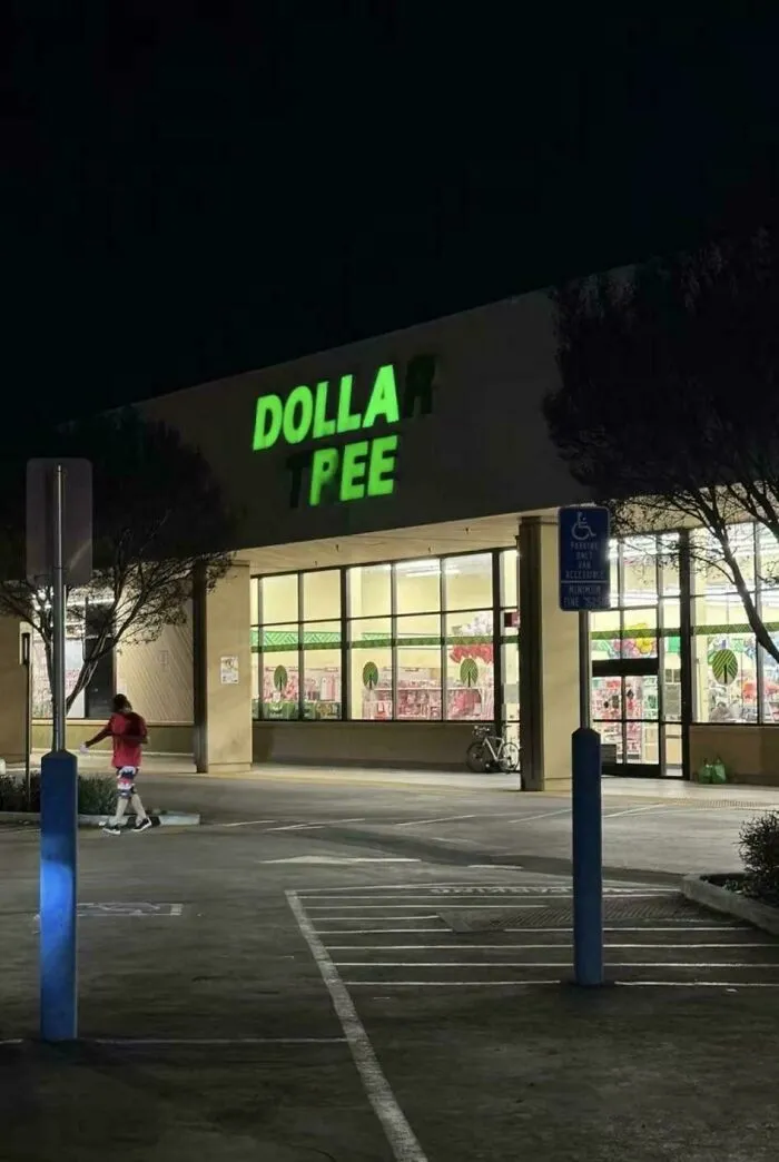 LED signs at night showing a partially lit store name with missing letters creating a funny display effect.