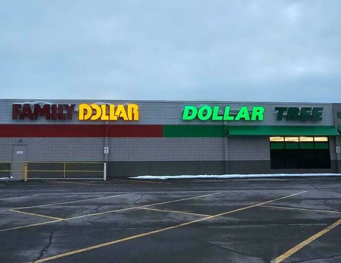 LED signs displaying Family Dollar and Dollar Tree store names illuminated against a gray sky at dusk.