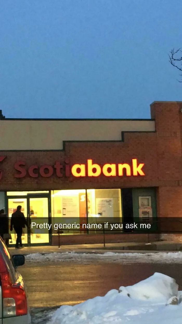 Partial LED sign of a bank building glowing at dusk with snow on the ground and a person entering the door