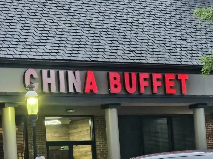 LED signs at a China Buffet restaurant with some letters brightly lit in red and others dimmed on the building facade.