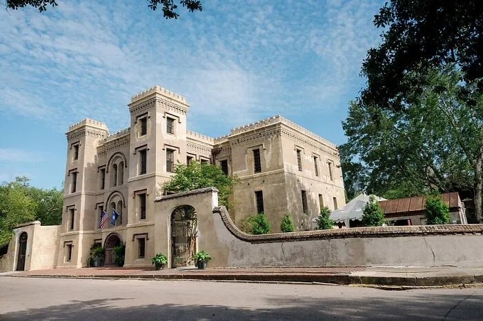 Historic spooky destination with haunted castle-like building surrounded by trees under a blue sky on a clear day