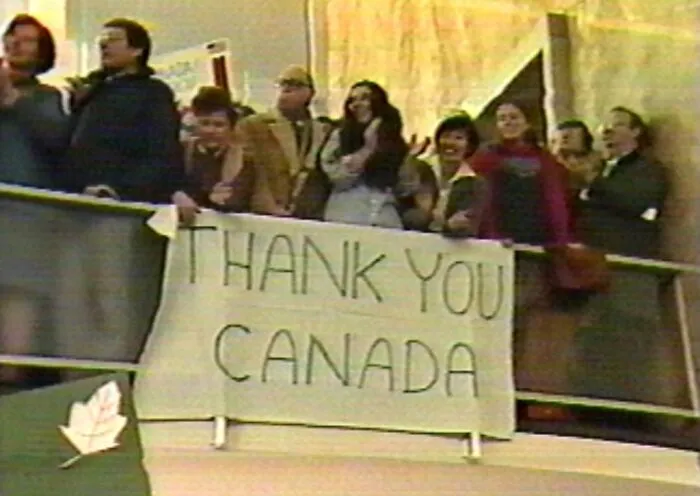 Grupo de personas con cartel de agradecimiento a Canadá en foto que representa la moda y estilo de los años 1980 wild.