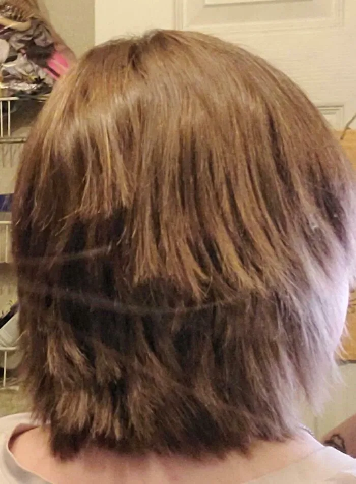 Peinado desastroso y cómico con corte irregular y cabello repentinamente dañado en un accidente capilar gracioso.