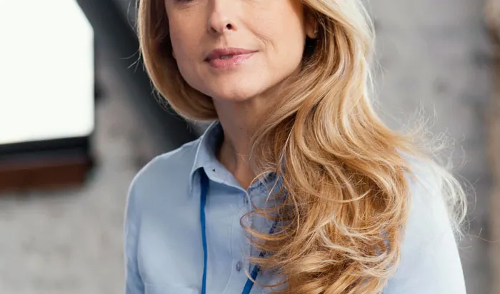 Woman with long blonde hair wearing a blue shirt, representing plastic surgeons discussing unnecessary surgeries.