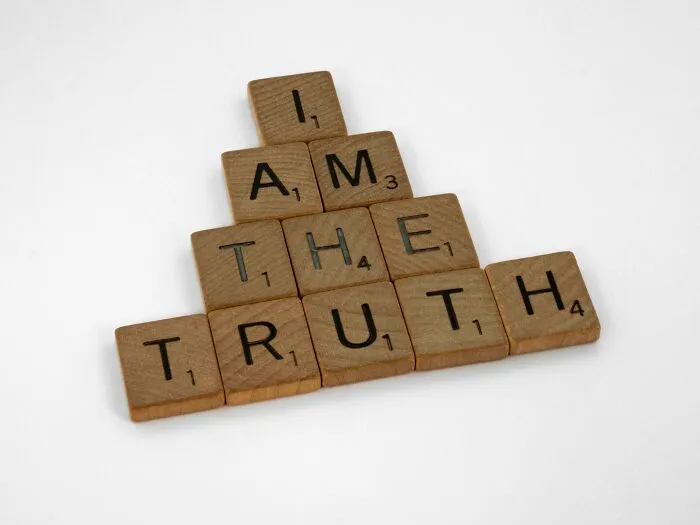 Wooden letter tiles arranged in a pyramid spelling I am the truth, symbolizing mind-bending scenarios challenging your morals.