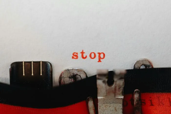 Close-up of a vintage typewriter typing the word stop in red ink, symbolizing mind-bending scenarios challenging your morals.