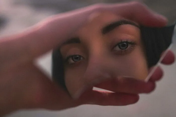Close-up of a person’s eyes reflected in a broken mirror piece, illustrating mind-bending scenarios challenging morals.