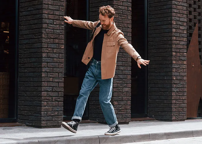 Man balancing on curb outside modern building, illustrating confidence and debunking common men myths.