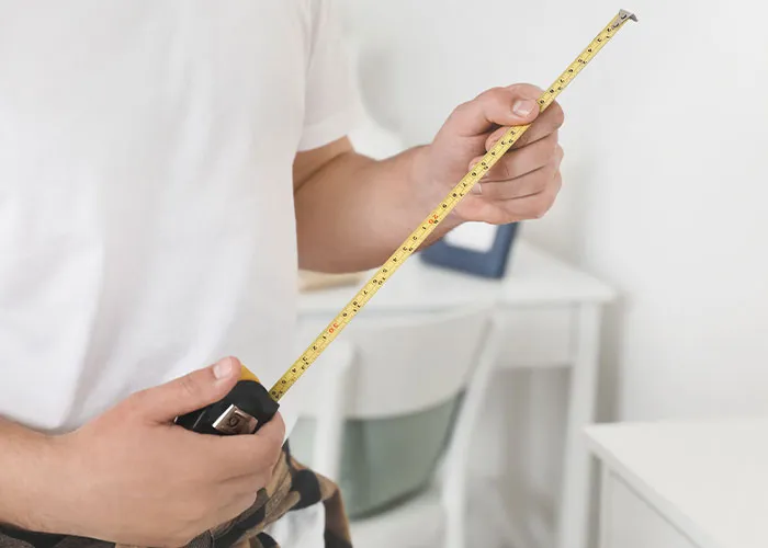 Man holding a tape measure in a casual room setting representing common myths about men that are simply not true.