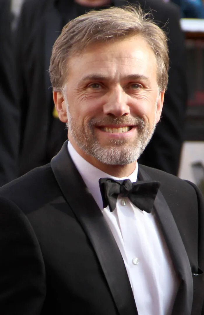 Male Hollywood star with a beard wearing a tuxedo and bow tie, representing stars who found fame after 30.