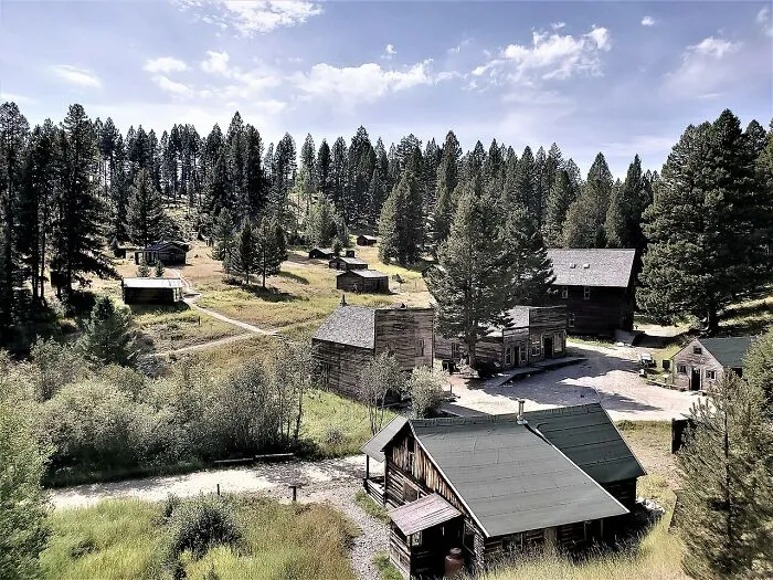 Abandoned rustic cabins and old buildings surrounded by trees in a spooky destination perfect for Halloween visits.