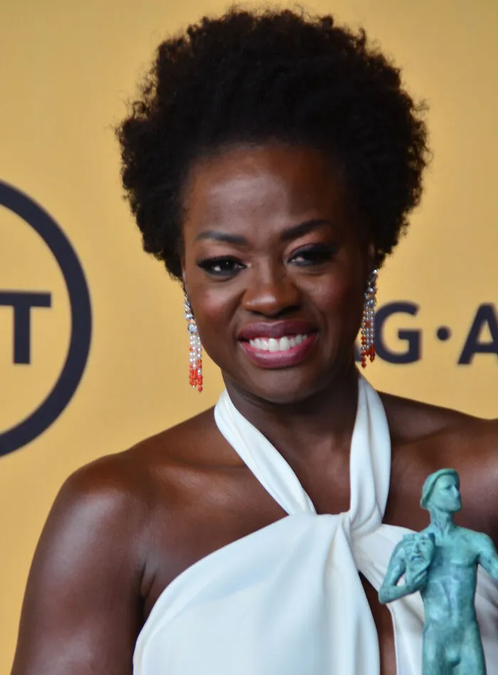 Smiling Hollywood star posing with award, representing actors who found fame after 30 in the entertainment industry.