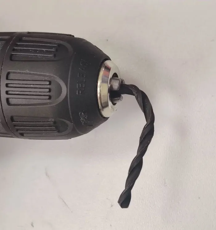 Close-up of a power drill with a bent drill bit showing a careless online shopping fail in tool purchase.