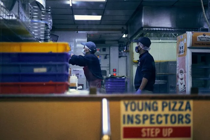 Two workers wearing masks preparing food behind a counter, illustrating people revealing longest grudges held.