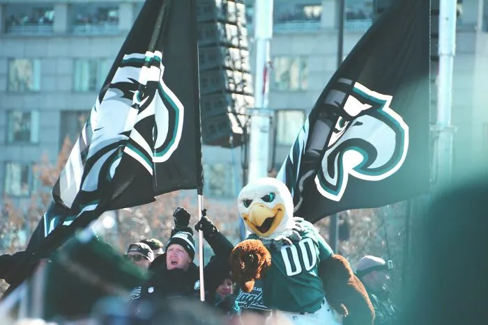 Crowd waving sports flags with a mascot in green jersey representing longest grudges people have held.