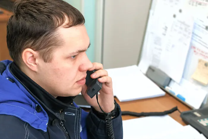 911 operator answering a strange emergency call in an office setting with papers and a phone on the desk.