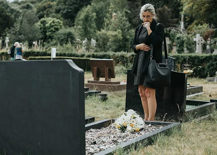 Woman in black mourning at a grave with flowers, reflecting on the real benefits of marriage for women.