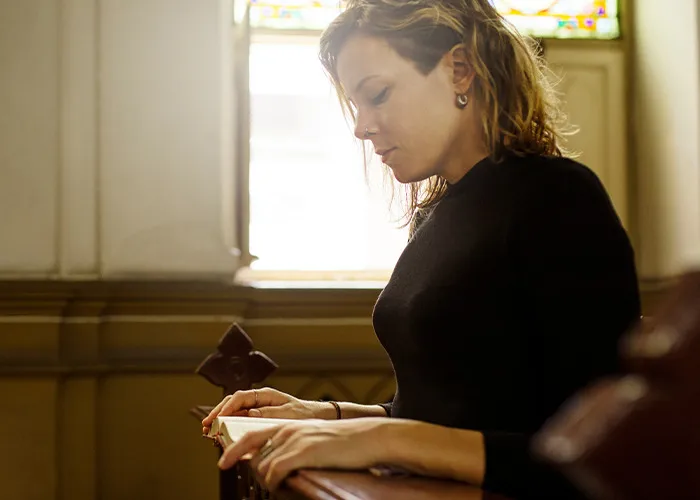 Woman reflecting thoughtfully in a church pew, symbolizing contemplation of benefits for women to get married.