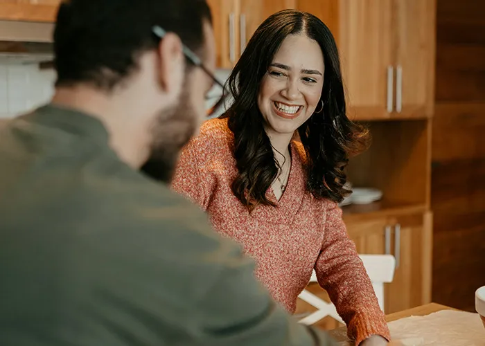 Woman smiling and talking with a man in a kitchen, discussing marriage benefits for women and their perspectives.