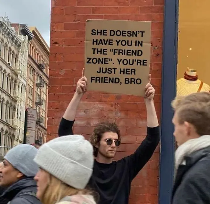 Man holding a humorous cardboard sign about the friend zone, featured in fight the patriarchy posts and memes.