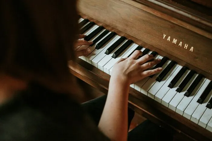 Person playing a Yamaha piano, illustrating the concept of dark secrets that could ruin people’s lives if revealed.