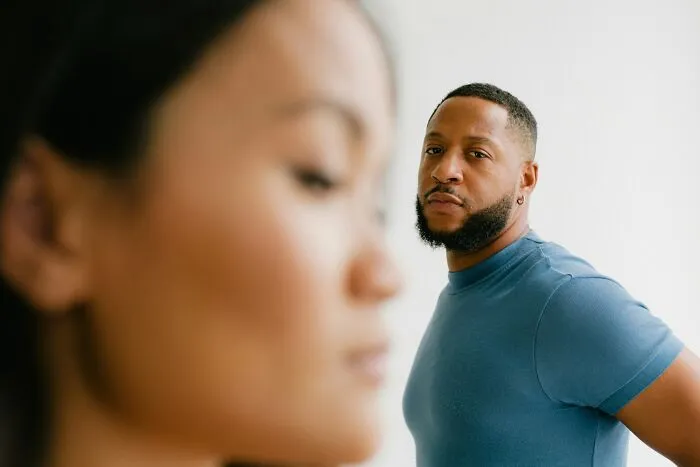 Man looking thoughtfully at woman in foreground, illustrating emotional impact of cheating signs in women.
