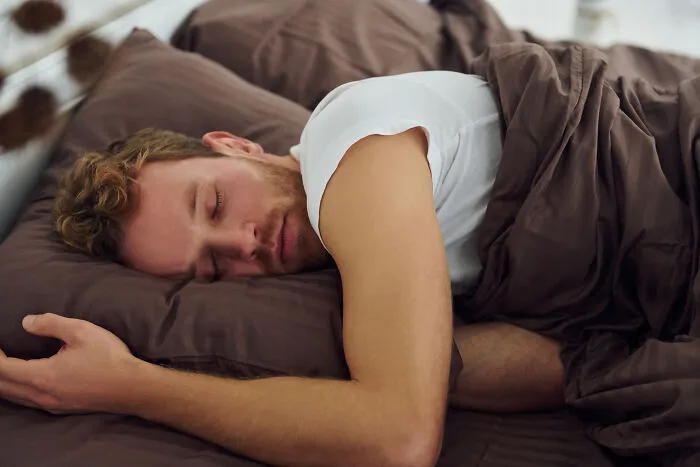 Man sleeping peacefully in bed while a pet’s intelligent behavior surprises and comforts its owner at home.