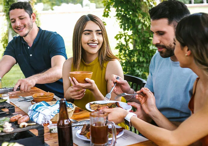 Group of friends enjoying a casual outdoor meal, highlighting social cues and moments that can lead to cringe-worthy misunderstandings.