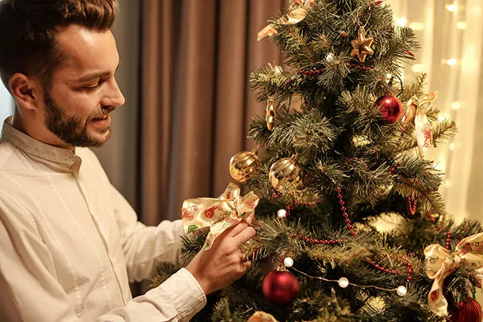 Man decorating a Christmas tree indoors, representing relationship red flags women didn't realize until after breakups.