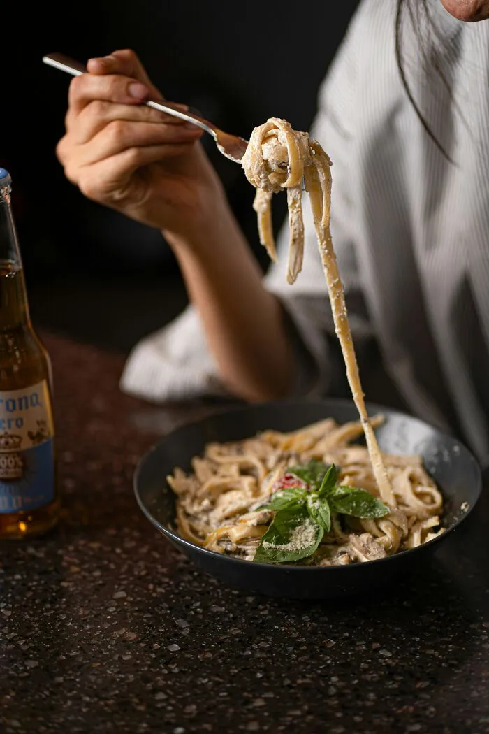Person eating pasta with fork, showing less popular foods in their country despite tourist expectations.