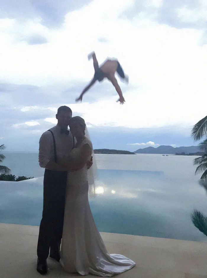 Pareja de novios posando junto a una piscina al atardecer mientras una persona cae al fondo capturando el momento antes del desastre.