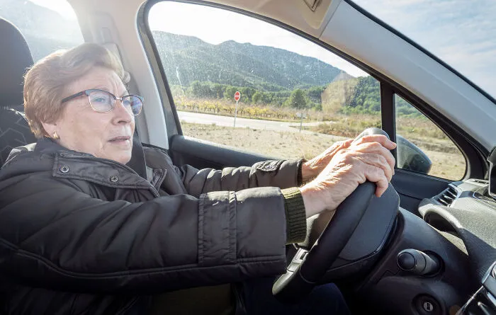 Elderly woman driving a car focused on the road, illustrating independence and smart use of loopholes.
