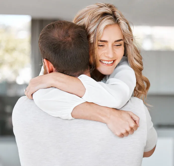 Happy woman hugging man tightly indoors, symbolizing people who disappeared to start new lives and reveal experiences.