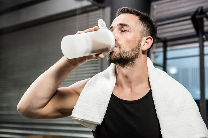 Man in gym with a towel drinking from a bottle, illustrating stories of little lies that backfired hard on people.