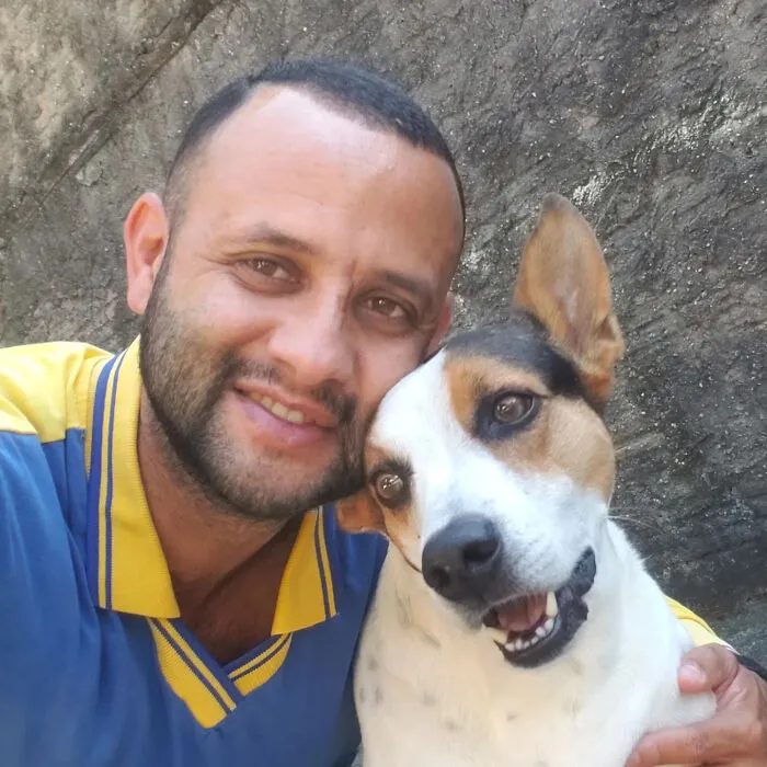 Mailman smiling with a happy dog, showing their close friendship on his daily delivery route.