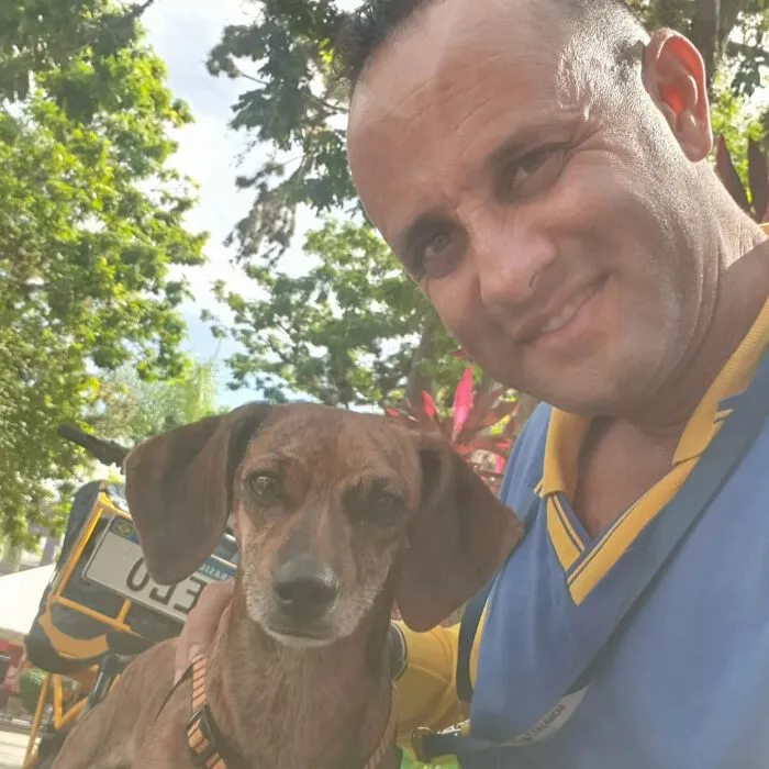 Mailman smiling with a brown dog outdoors surrounded by trees, showing the bond between mailman and dogs on his route.