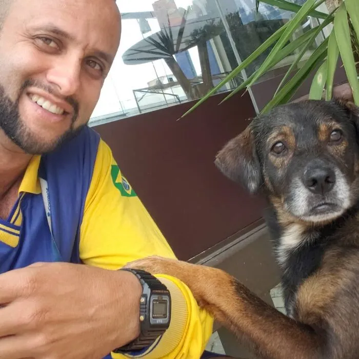 Mailman smiling with a dog, showing friendship and connection on his delivery route outdoors.