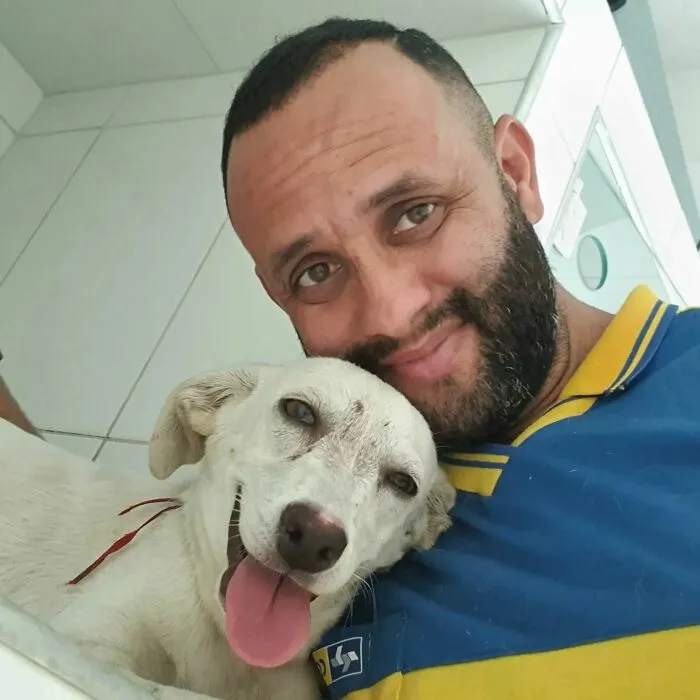 Mailman smiling with a happy white dog, showing the close bond between the mailman and dogs on his route.