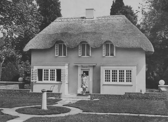 Casa antigua con techo de paja y persona en la entrada, una foto rara y poderosa de historia.