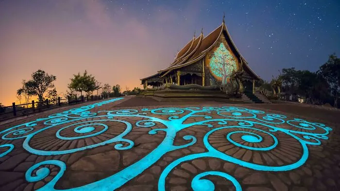 Temple with glowing blue tree patterns on ground and walls under a dusk sky, likely from where was this taken posts.