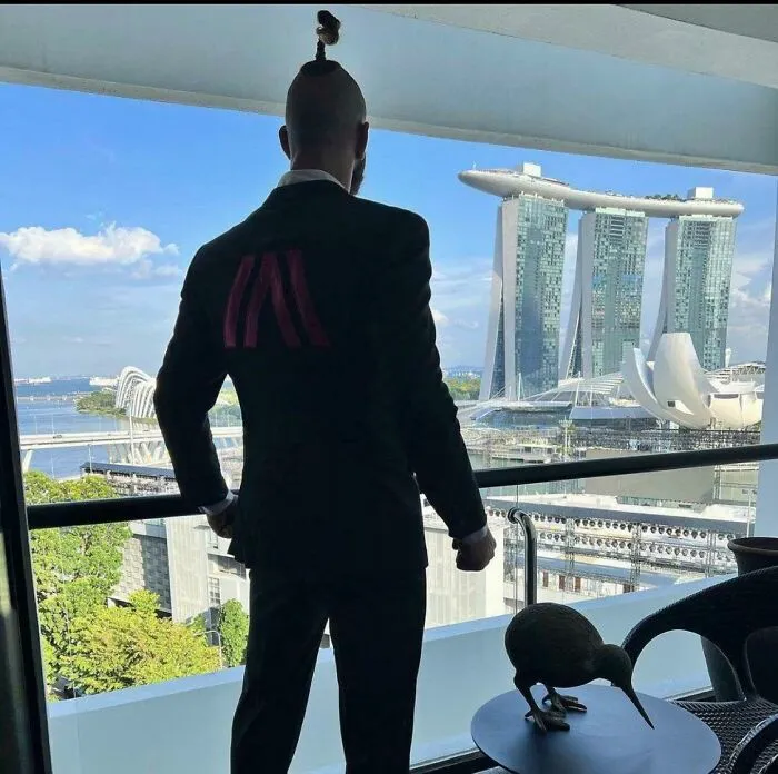 Man in a suit looking out at the Marina Bay Sands building, featured in popular where was this taken posts.