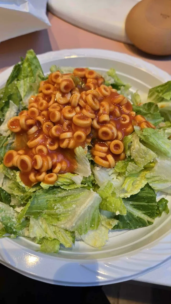 Plate of lettuce topped with canned pasta rings in tomato sauce, an example of dishes that are just stupid.