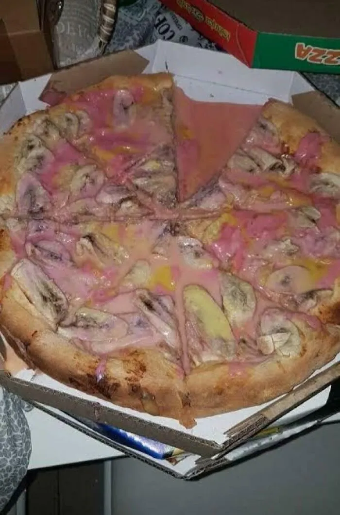 Pizza with unusual pink sauce and banana slices in a delivery box, one of the dishes that are just stupid in appearance.