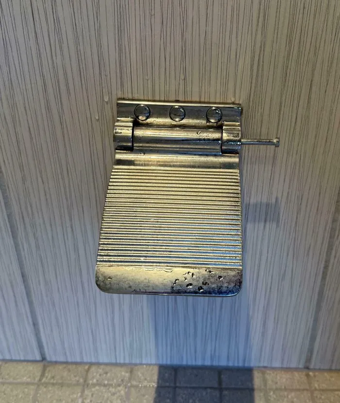 Pestillo metálico reutilizado como solución ingeniosa para problemas cotidianos en puertas de madera.