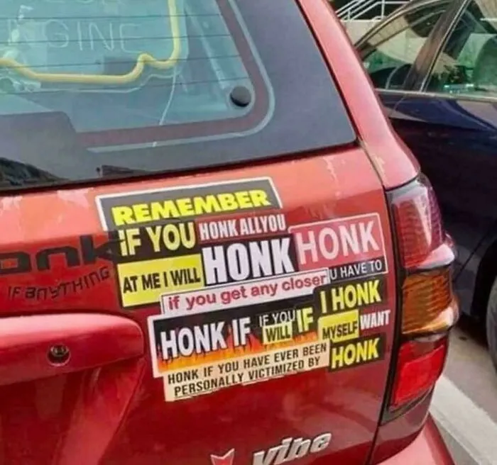 Red car covered in confusing and excessive honk warning stickers, a clear example of failed attempts to make cars cooler.
