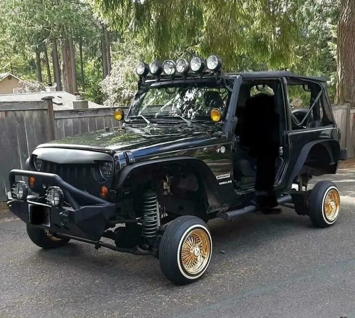 Black Jeep with missing rear wheels and gold chrome rims, an example of stupidity on wheels and failed car customization.