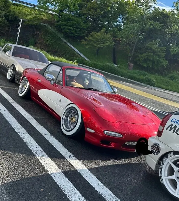 Red car with unusual white side panel and lowered wheels shows an example of stupidity on wheels in car modifications.