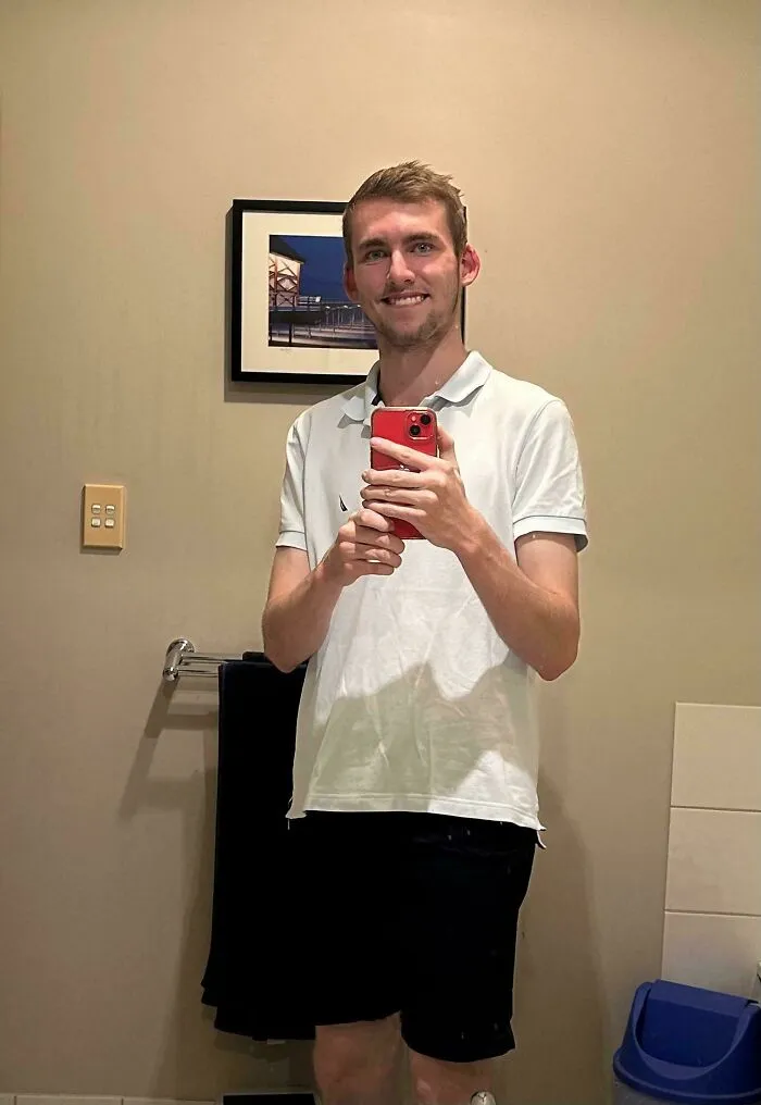 Young man smiling taking a selfie in a bathroom mirror showcasing wholesome internet moments and positive online presence